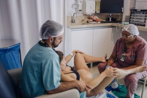 Pai, doula e gestante unidos no nascimento.